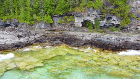 flying to cliff full of caves and lush green vegetation on the slope bruce peninsula, georgian bay