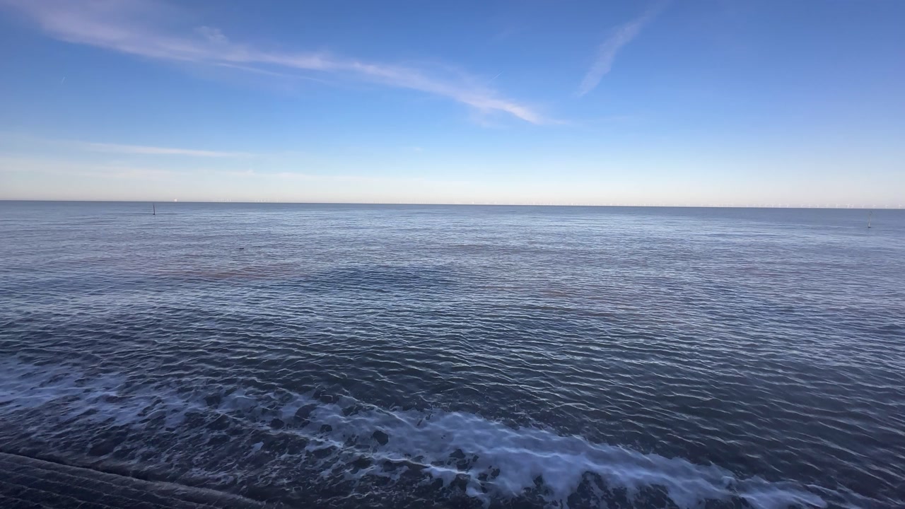 Aerial drone view of calm open sea with gentle waves and wide horizon under clear blue sky creating peaceful minimal seascape and natural marine environment