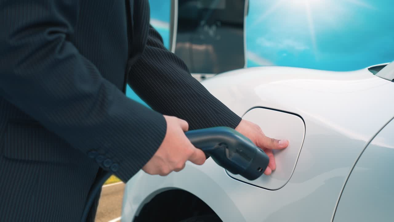 İlerici iş insanı yolculuğu sırasında tepede elektrikli aracını şarj ediyor.