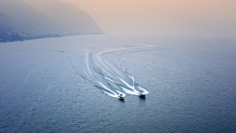 Filmische-Luftdrohnenansicht-Von-Zwei-Schnellbooten,-Die-Auf-Dem-Iseo-See,-Italien,-Rennen