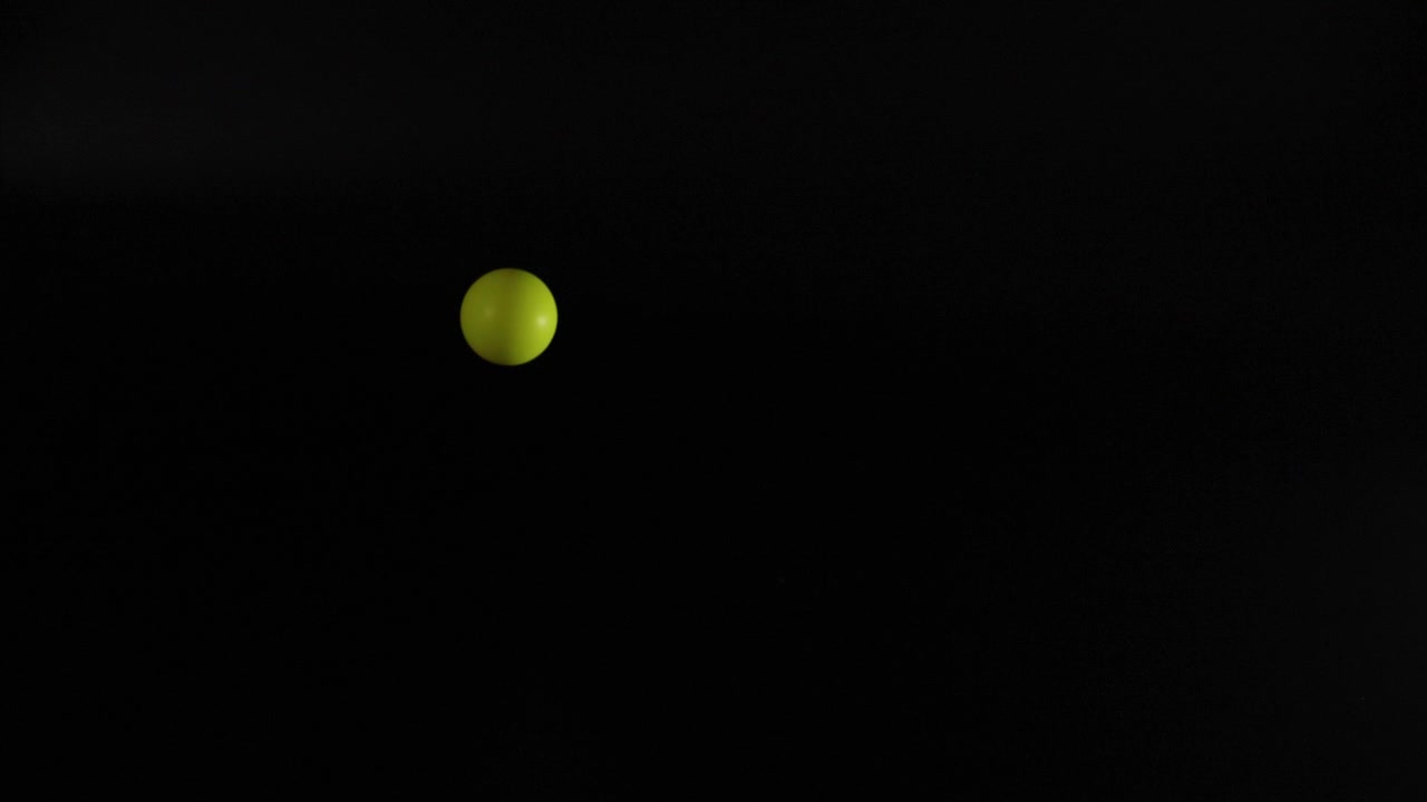 A yellow ball bouncing in darkness