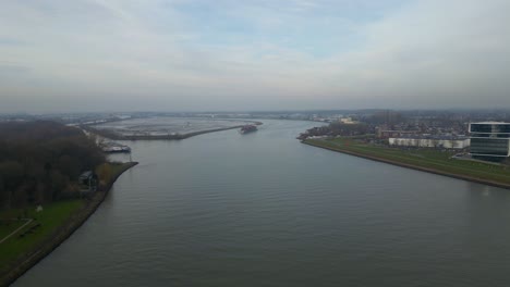 Drone-dolley-aerial-shot-of-a-ship-sailing-on-the-river-between-the-dutch-landscape