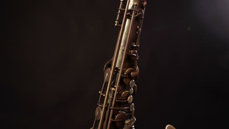 Tilt-up-and-down-shot-of-vintage-sax-on-stand,-dark-background