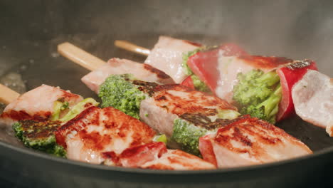 cooking salmon skewers with broccoli and vegetables