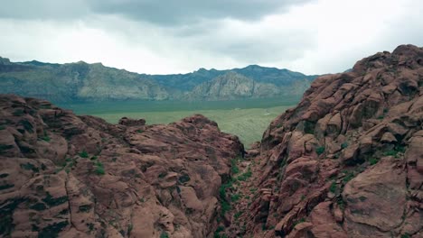 Aerial-flying-through-a-notch-in-Red-Rock-Canyon-to-reveal-the-valley-below