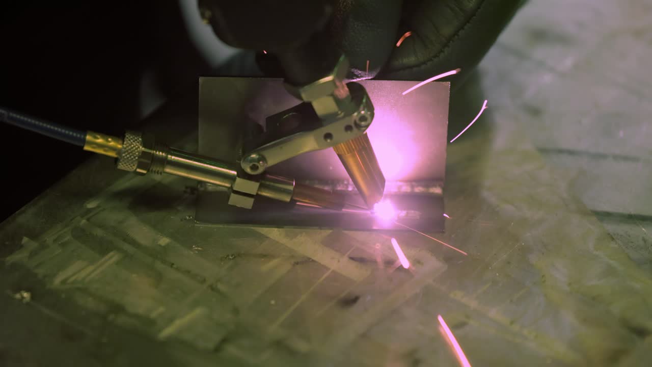 Laser welding machine with hand hold gun. Laser welding is shown in close-up.