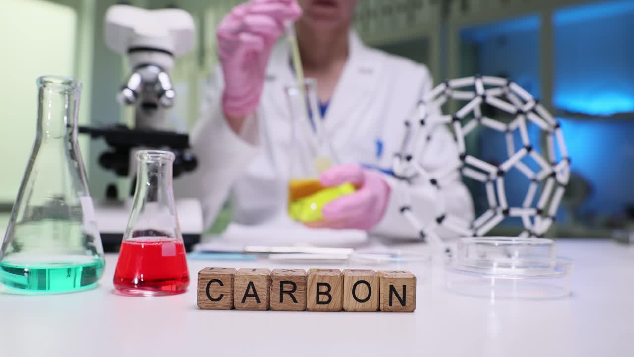 A scientist working in a laboratory with 'CARBON' blocks on the table