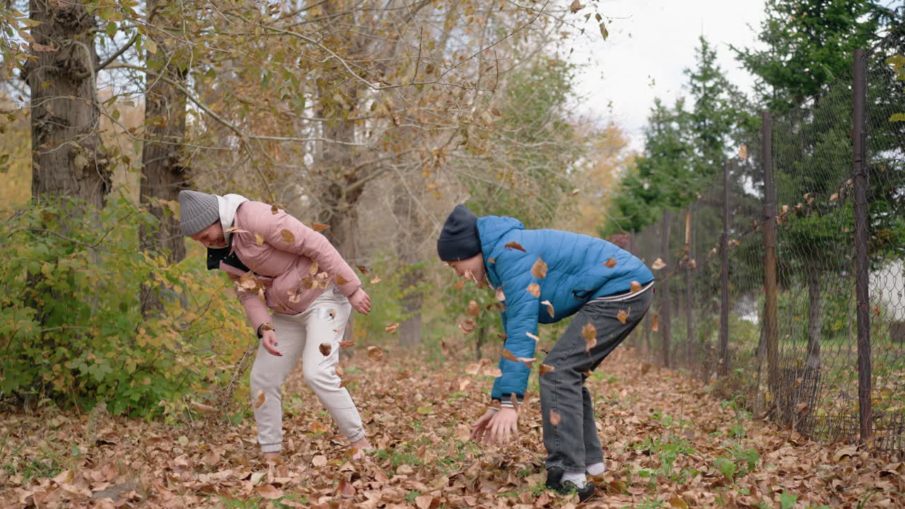 행복한 형제자매들이 야외에서 즐겁게 놀고, 마른 가을 잎자루를 서로 던지고, 활기찬 가을 색과 자연에 둘러싸인 함께 놀이하는 순간을 즐기고 있습니다.