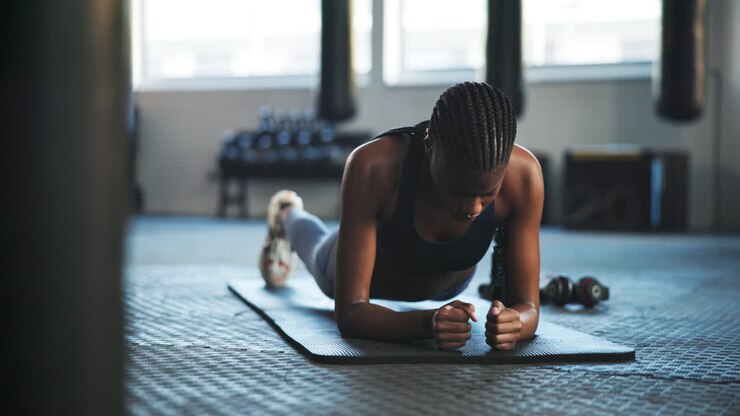 Serious, plank and a black woman at the gym