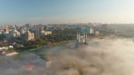 entrance to the central road artery of the city of ufa . view to ar-raheem under construction mosque in light fog. aerial flight view.