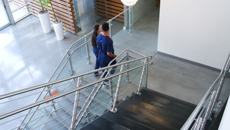 male doctor and female nurse walk up the stairs in hospital