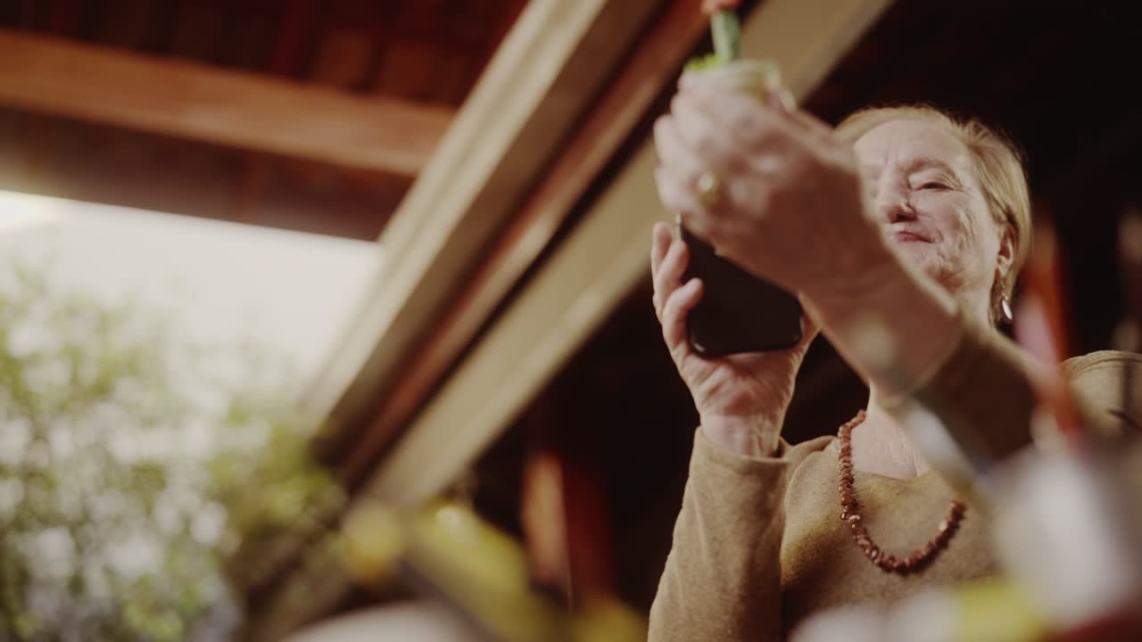 An elderly woman captures photos with her smartphone outdoors