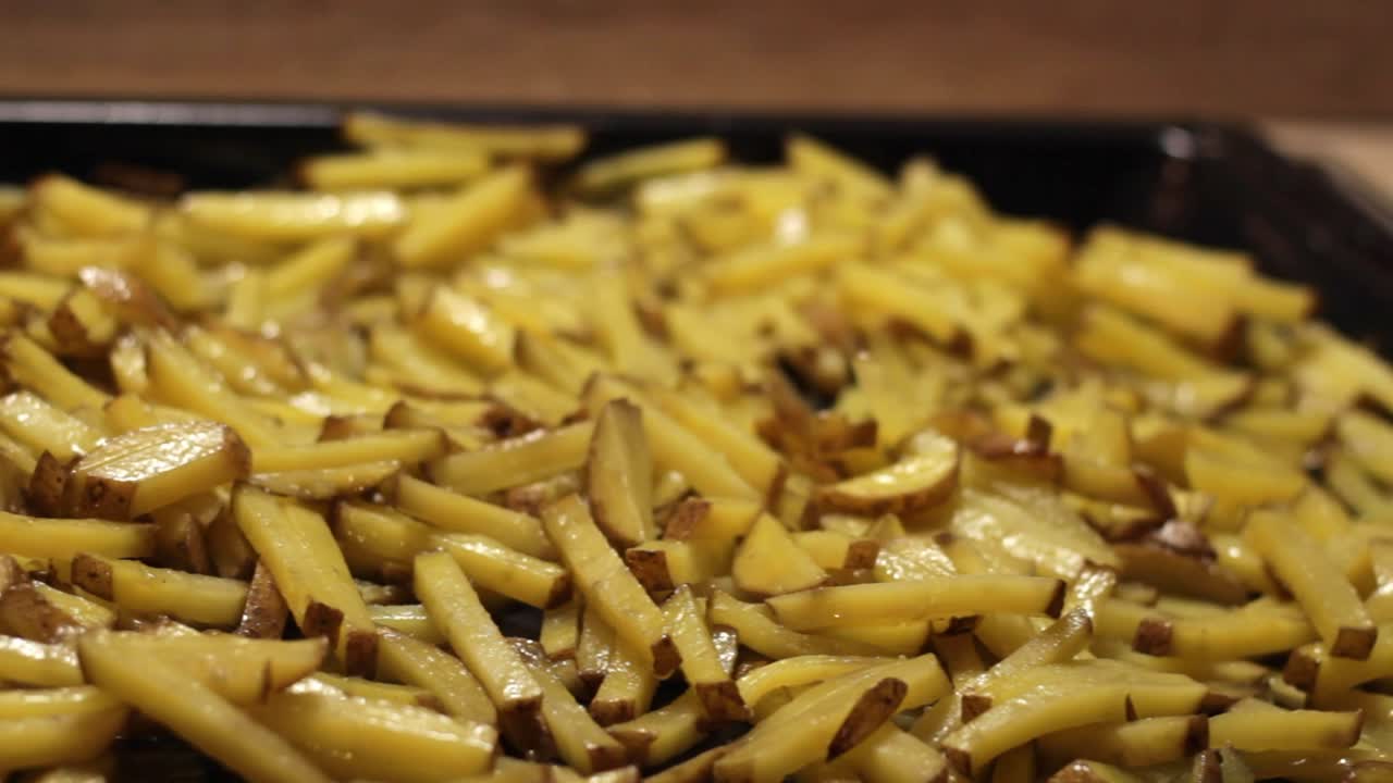 Baking fresh yellow potatoes stirring with a wood spatula - preparing at home