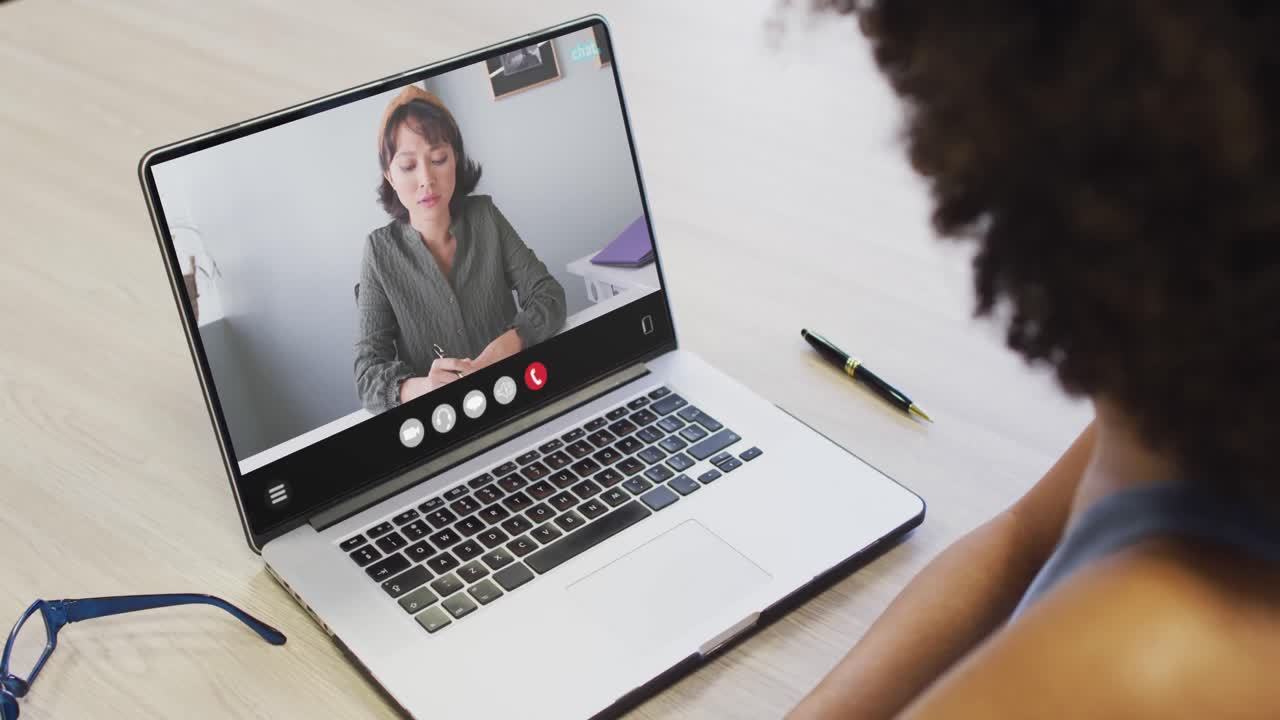 African american woman using laptop for video call, with business colleague on screen
