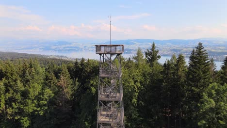 aerial drone shot flying up and over pfannenstiel observation tower and revealing lake zürich in the background