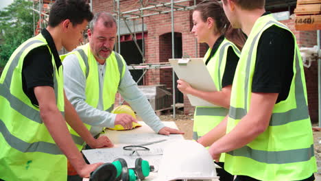 builder on building site discussing work with apprentices