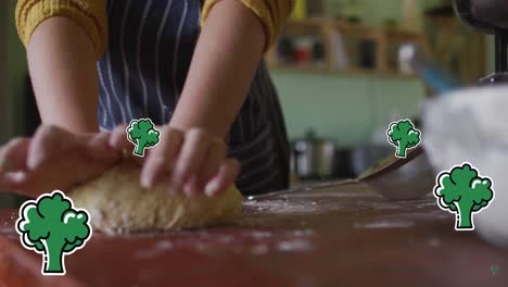 Animation-of-broccoli-icons-over-caucasian-woman-cooking