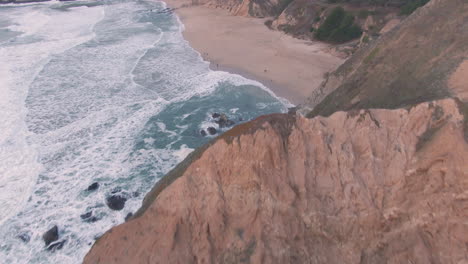 cliff side beaches with pacific waves crashing below winter sunset aerial flight