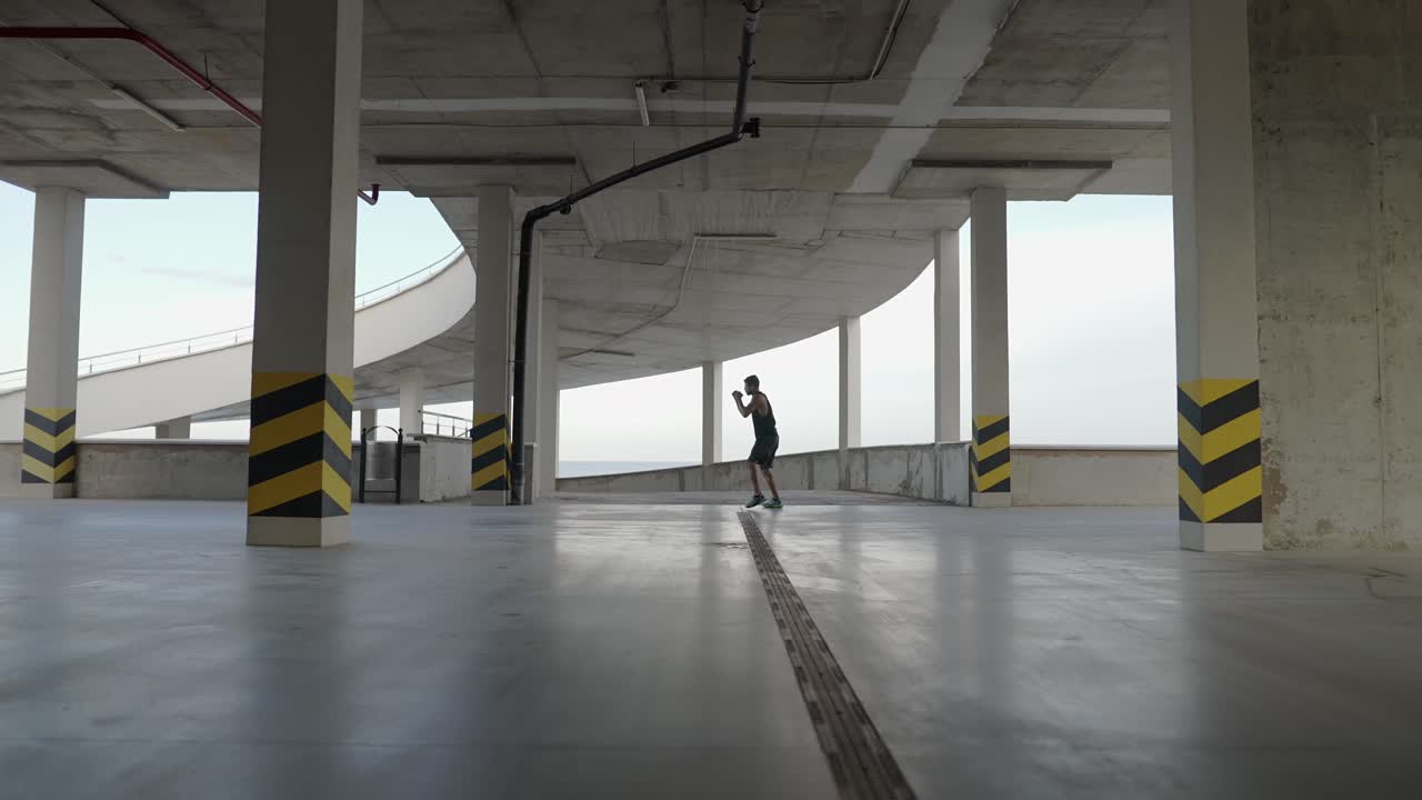 Young boxer train in a parking garage, battle with the shadow