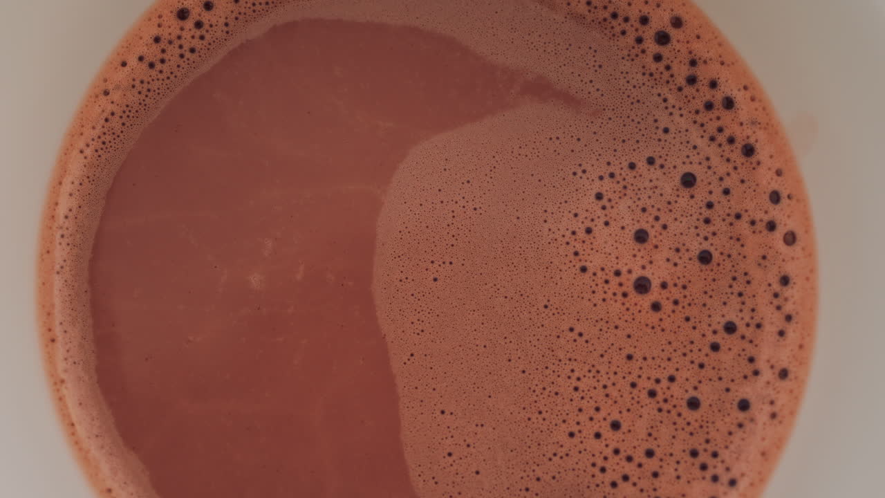 Vista dall'alto di una tazza calda di cioccolata calda o caffè con schiuma cremosa e bolle sulla superficie