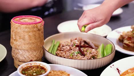 hand squeezing lime over traditional thai food