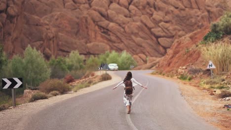 a young adventerous woman walking down the bendy road in the death valley in america on the hottest day of the year