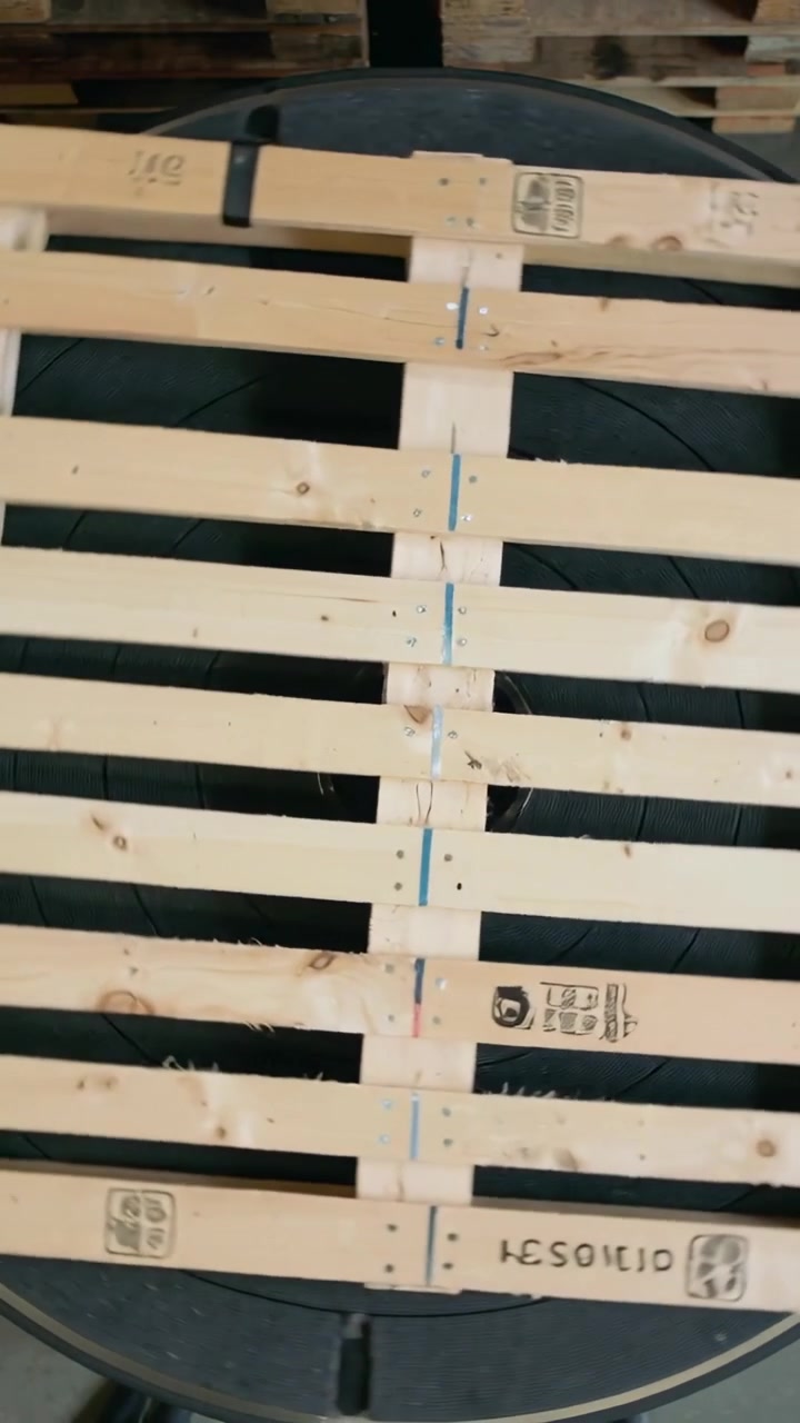 Video verticale: Pallet di legno in rotazione mentre la telecamera si sposta su un fusto, rivelando timbri in un magazzino.