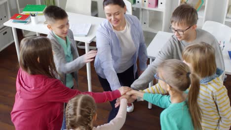 six teenage kids joining hands together with teacher