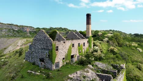 abandoned overgrown ivy covered desolate countryside historical welsh coastal brick factory mill aerial view establishing rise right shot