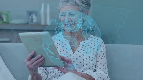 animation of globe and world map over happy senior caucasian woman using tablet at home