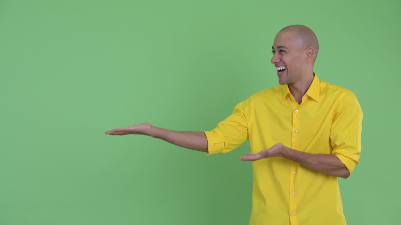 Happy handsome bald businessman showing something