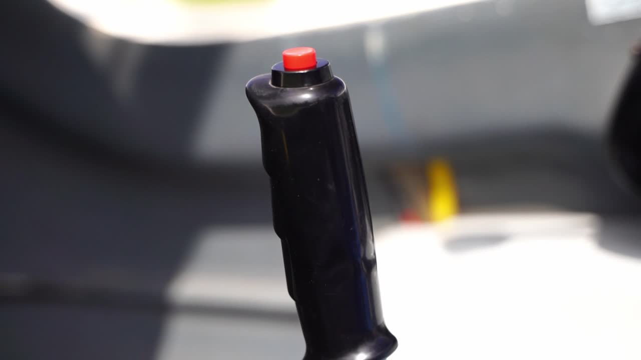 Black joystick with a small red emergency button in the middle