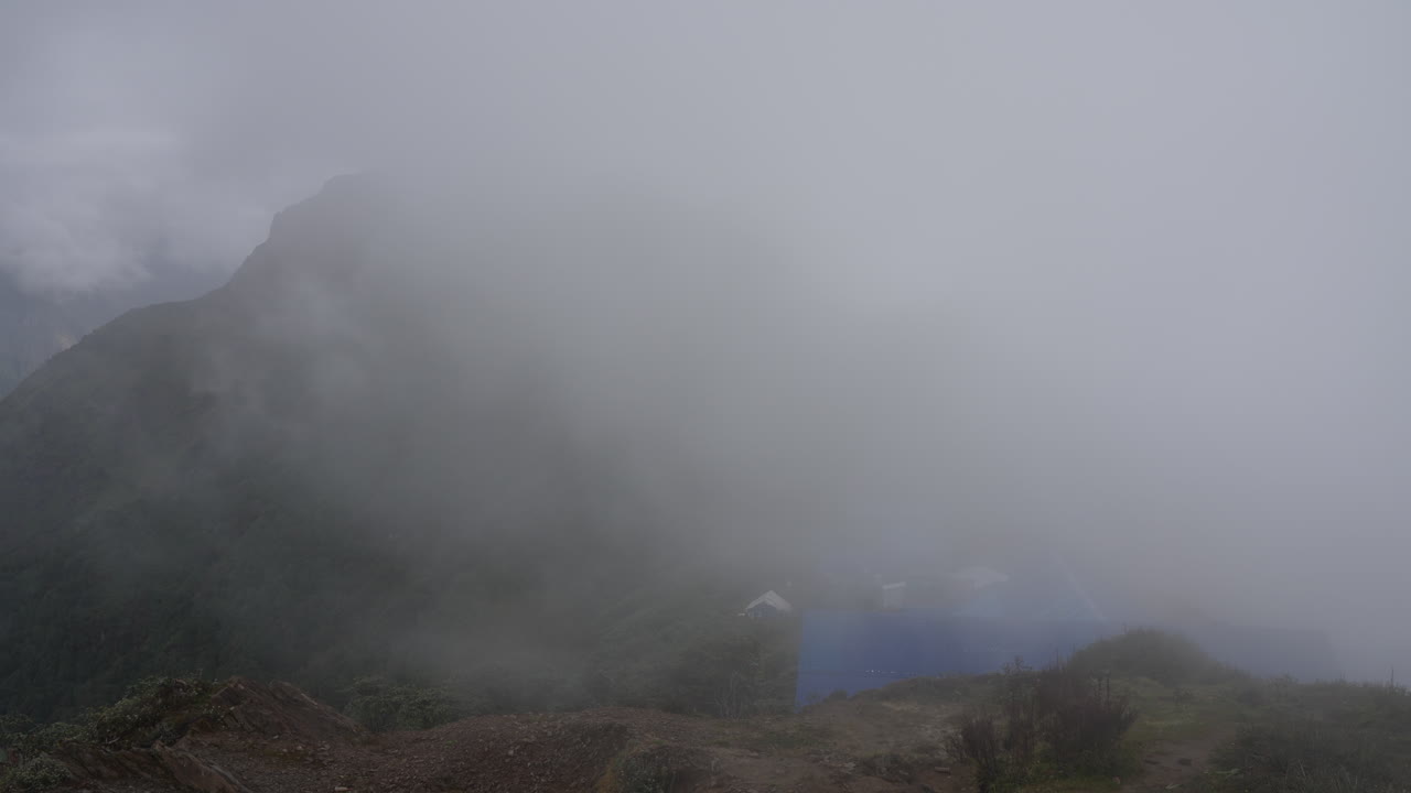 히말라야 산맥 의 가파른 알파인 목초지 의 전망 은 아침 초 에 안개 와 구름 이 트레커 들 의 경로 에 있는 마디 히말라야 고등 캠프 를  ⁇ 쓸고 있다
