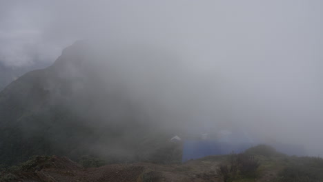 una vista de la empinada pradera alpina en las montañas del himalaya mientras la niebla y las nubes de la madrugada barren el campamento alto del mardi himal en la ruta de los excursionistas