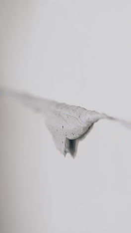skilled plasterer smears excess glue on white gypsum pasteboard construction holding small putty knife close view
