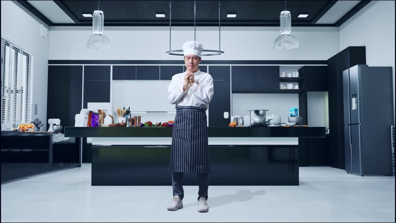 cuerpo lleno de hombre asiático chef orando por algo mientras estaba de pie en la cocina de casa
