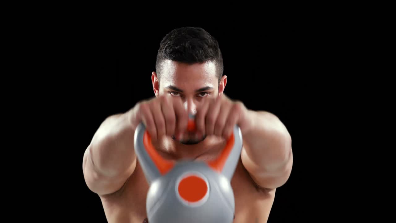 심각한 근육 남자가 케틀벨을 들어 올립니다.