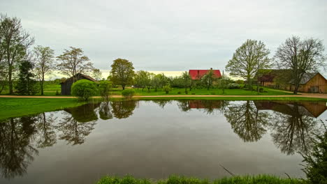 Time-lapse-shot-of-changeable-weather-with-grey-clouds-and-sunset-colors-at-tranquil-park-with-lake-in-autumn