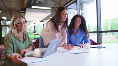 Equipo-De-Negocios-Femenino-Multicultural-Sentado-En-El-Escritorio-Con-Una-Computadora-Portátil-En-La-Oficina-Colaborando-En-El-Proyecto