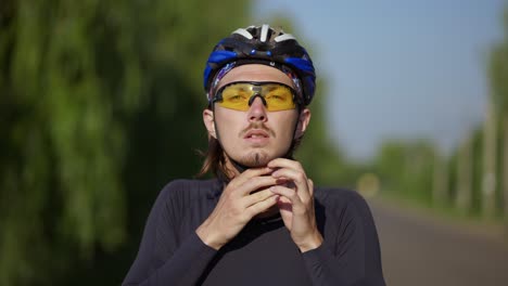 Sportsman-putting-on-his-helmet-on-a-bicycle,-close-up