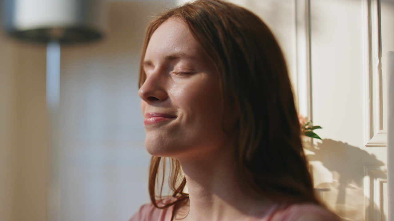 Donna serena che si gode la mattinata a casa, in primo piano. Ragazza calma e sorridente che sogna.