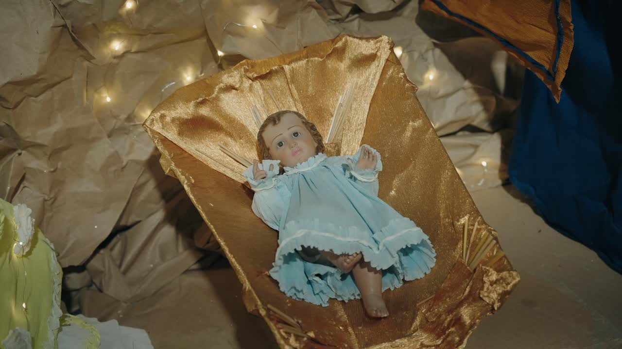 estatuilla del bebé jesús en un vestido azul en tela dorada, escena de la natividad de navidad