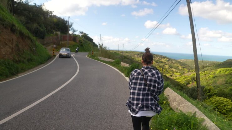 Donna che cammina su una strada di montagna panoramica con vista mare
