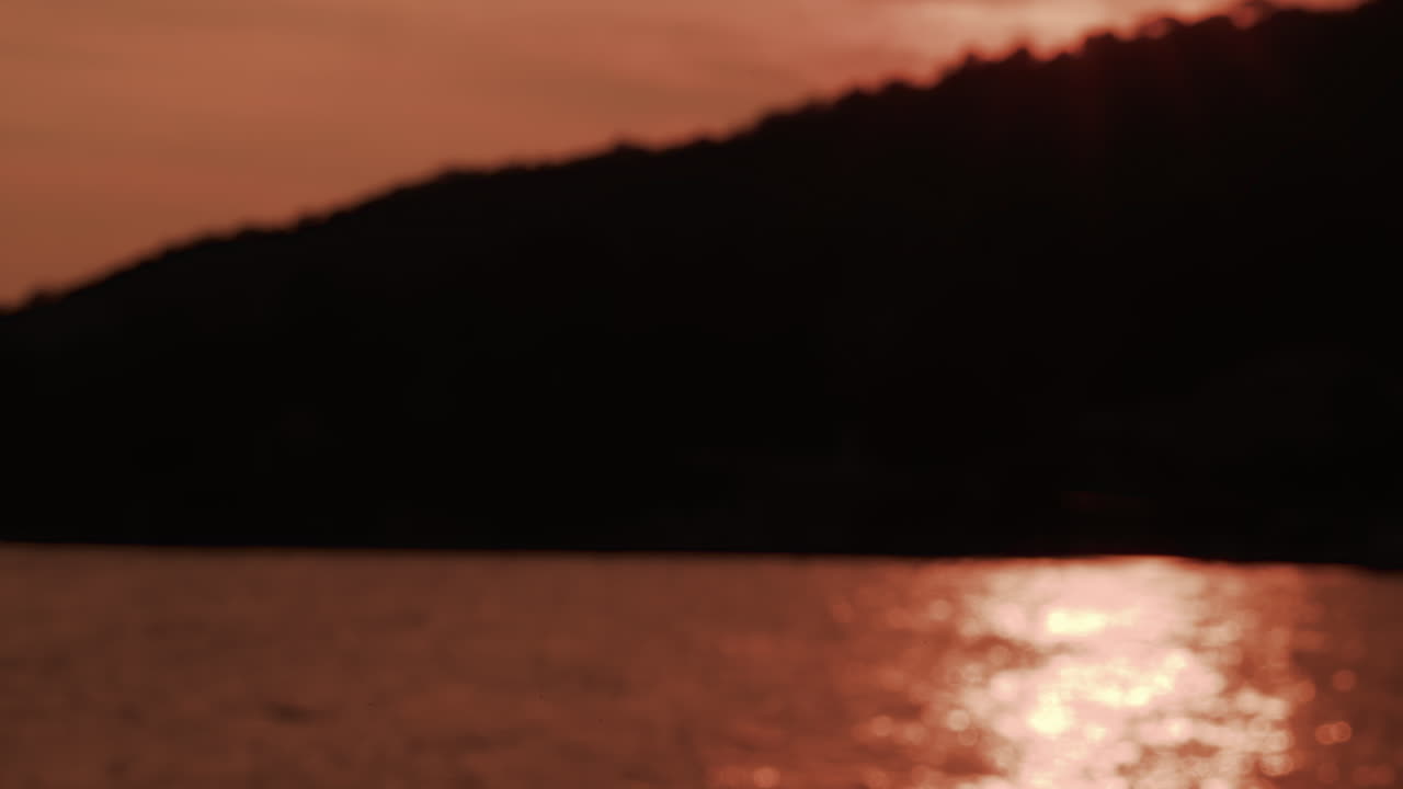 A dramatic sunset view showing a dark cliff silhouette with golden sunlight shimmering across the sea