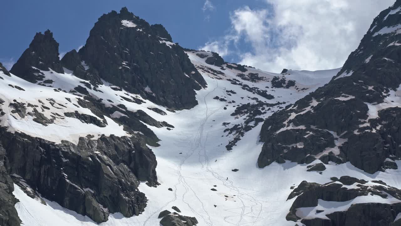 Persone che praticano freeride lungo il pendio roccioso di una montagna innevata