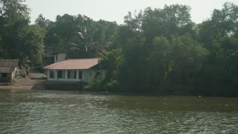 casa a la orilla del río enclavada entre árboles tropicales con la luz del sol reflejada en el agua, serena y aislada