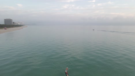 el paddleboarder y el navegante son solo personas en la playa brumosa de la mañana, miami