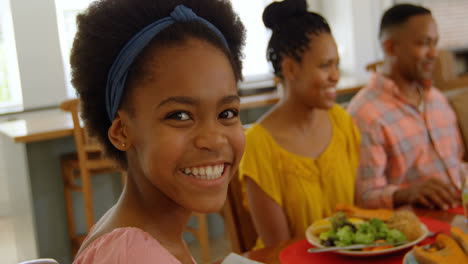 Front-view-of-black-girl-having-food-with-her-family-at-dining-table-in-a-comfortable-home-4k