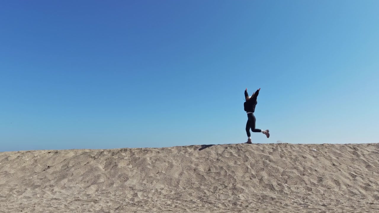在陽光普照、藍天白雲下，有人在沙灘上跑步，享受戶外活動。