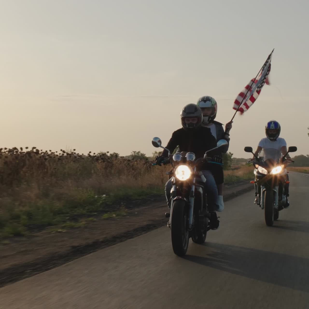 한 무리의 젊은이들이 석양에 오토바이를 탄다